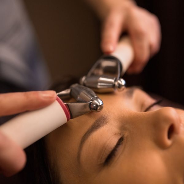 Professional aesthetician expertly applying a facial rejuvenation device on a client.